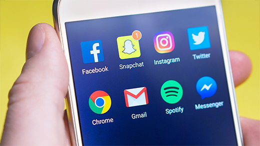Photo of hand holding smartphone with apps on it Photo of hand holding smartphone with apps on it