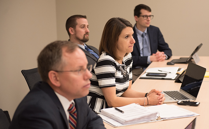 Photo of MBA students at a table listening to a lecture