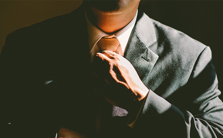 Photo of man in suit straightening tie