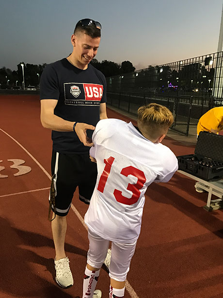 Adam Hoffman ’18 assists a young  USA Football player with ta Catapult Tracking Device prior to the game.