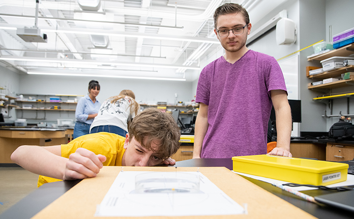 William Warren and lab partner Matthew Oros '24 eye the precision of their physics lab setup.
