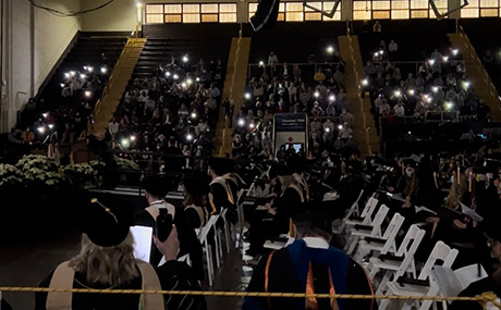 Mobile phone lights shine in the waning moments of commencement after windy weather caused a power outage.