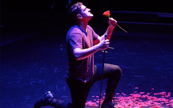 Male music theatre student kneeling during performance 