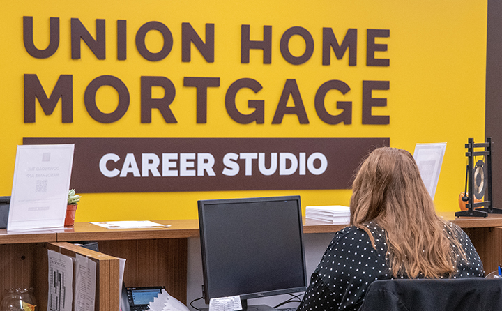 BW Career Studio Sign with Woman Sitting in Front of Computer