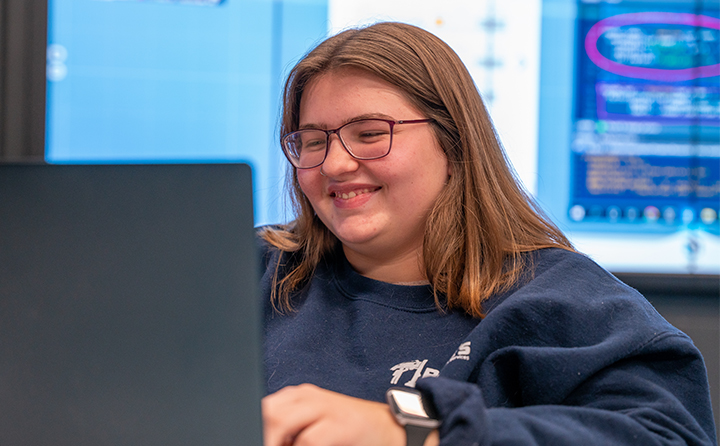 Data science student smiling and looking at laptop