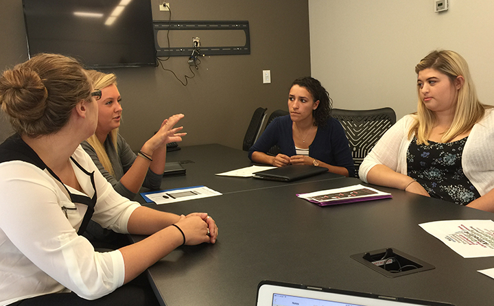 Photo of BW students sitting at a conference table discussing marketing plans