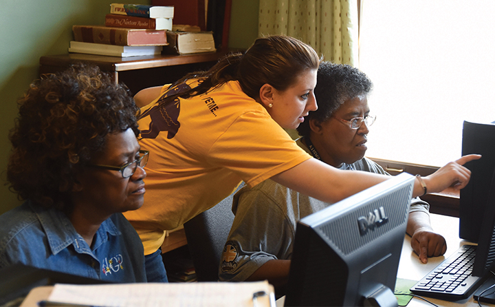Photo of student helping two women on computers