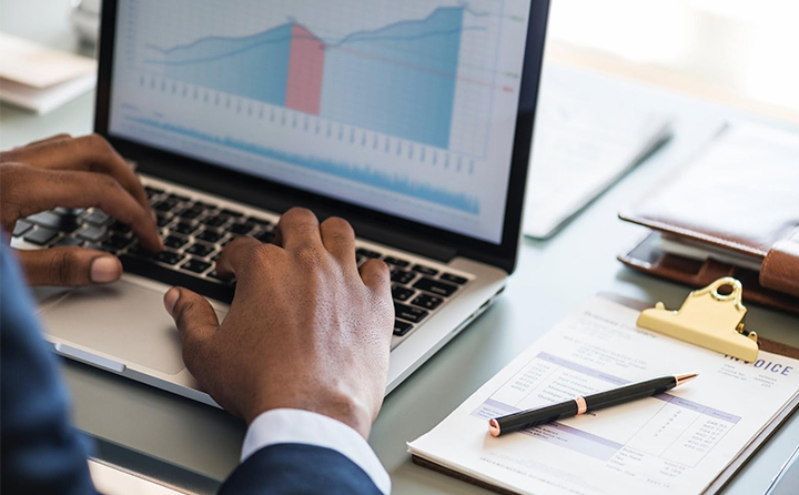 Photo of person typing on a laptop with a business chart on it