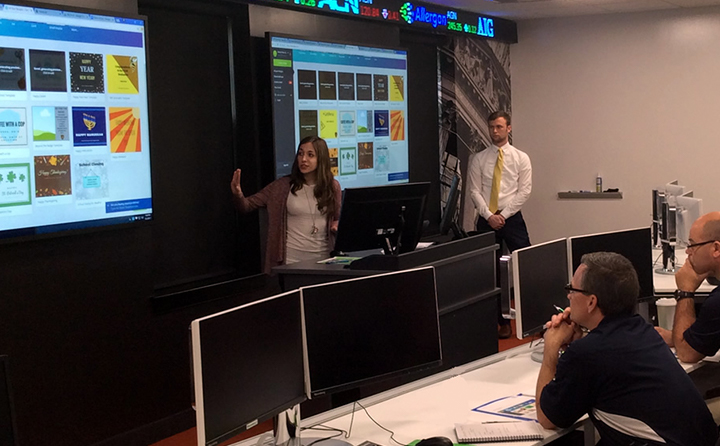 Photo of students giving a presentation in front of large screens