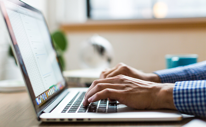 Photo of hands typing on a laptop keyboard