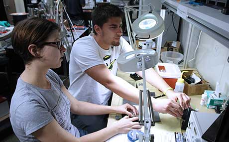 Photo of Austin Conn (r) and Michelle Salem (l) working with fiber optic cables at the University of Oregon.