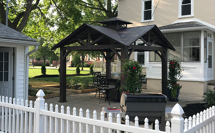 The completed rear patio includes a pergola, gas fire table, grill and raised garden beds.