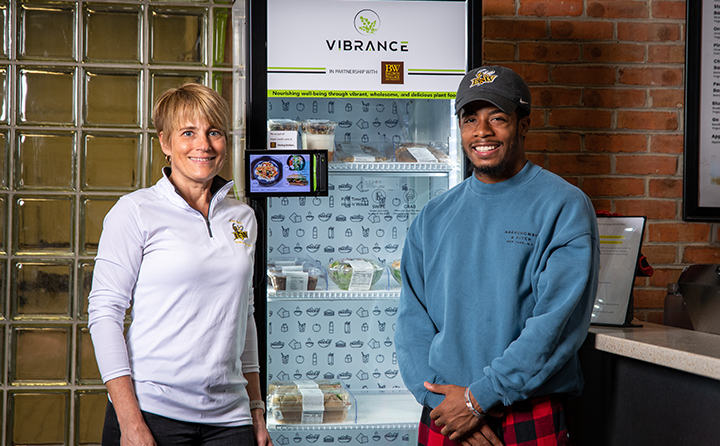 Professor Wendy Hyde (left) and Jaden Hinton '24 (right) near one of two new Vibrance food kiosks on campus.