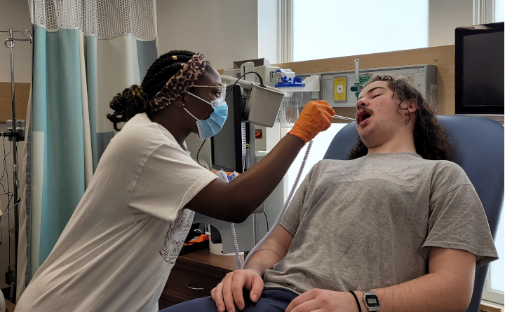 Nursing student Ruth Ajiboye checks acting student Quin "Mugs" Johnson's temperature.