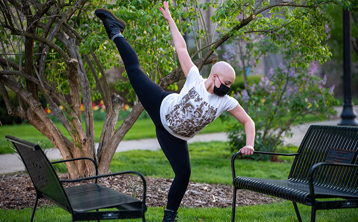 BW dance student holding a post next to an outdoor bench