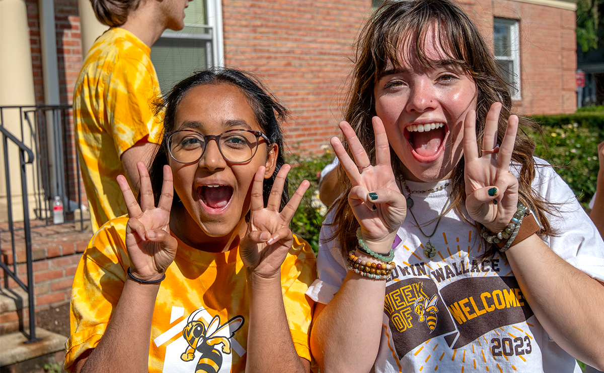 Two students use their fingers to show three for the incoming class year