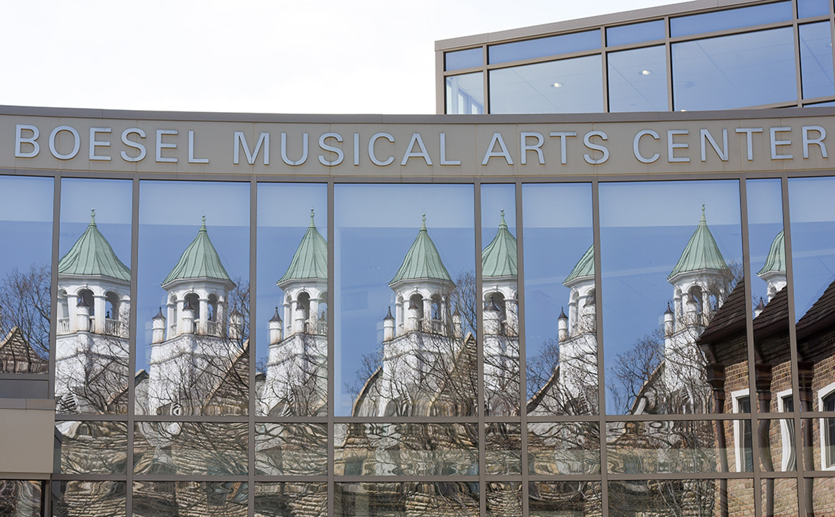 The glass front of BW's Boesel Musical Arts Center reflects Marting Hall tower.
